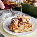 Maple syrup is being pour over a piece of almond croissant french toast bake