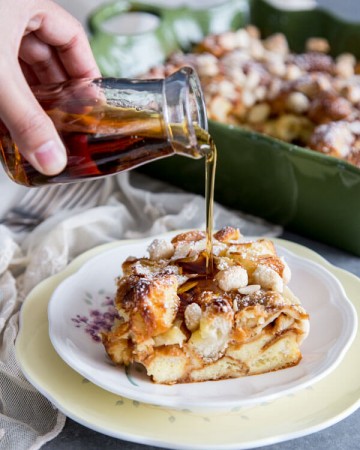Maple syrup is being pour over a piece of almond croissant french toast bake