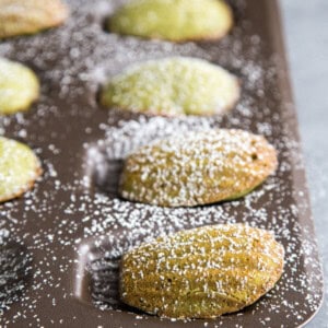 Matcha madeleines dusted with powder sugar in a madeleine pan
