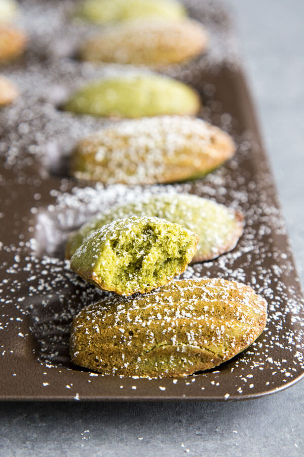 Matcha madeleines dusted with powder sugar in a madeleine pan
