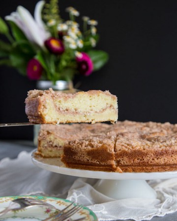 A slice of buttermilk coffee cake is lifted from the cake stand