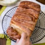 Cinnamon pull apart bread on a round wire rack being pulled apart.