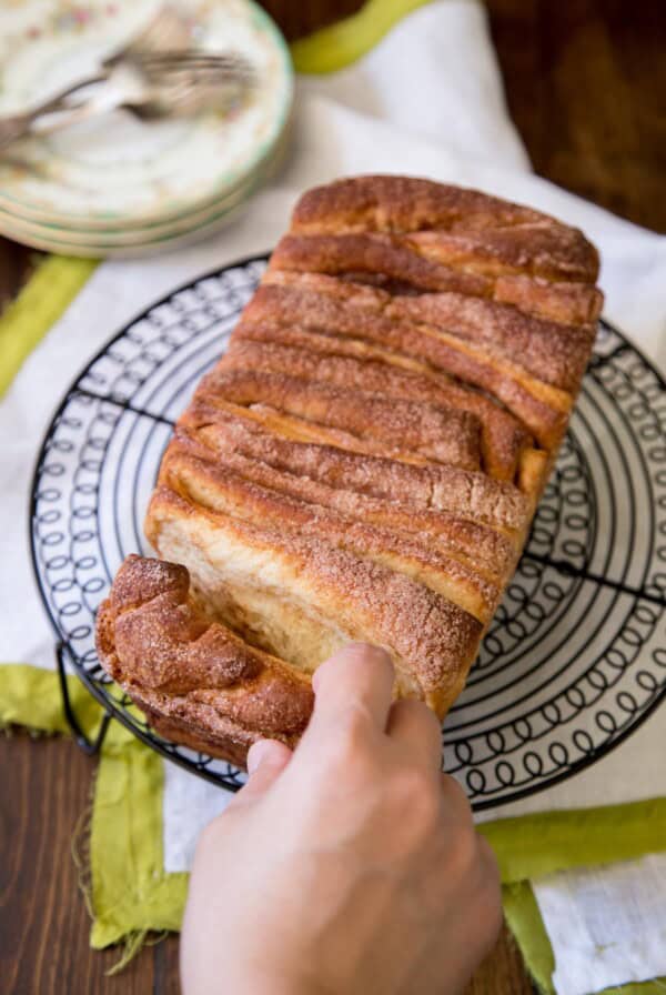 Cinnamon pull apart bread on a round wire rack being pulled apart.