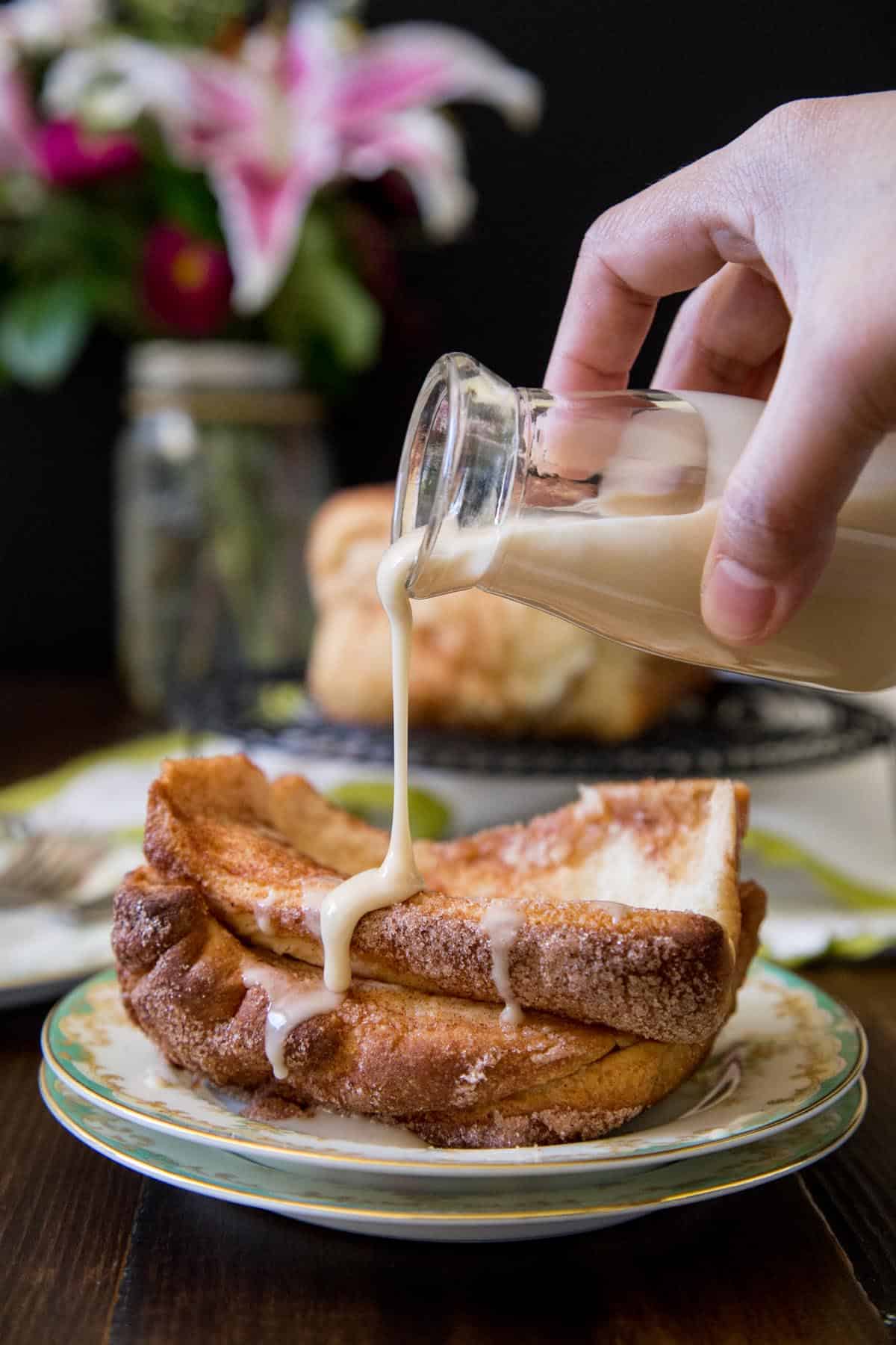 Maple glaze drizzling over a portion of cinnamon pull apart bread on a plate.