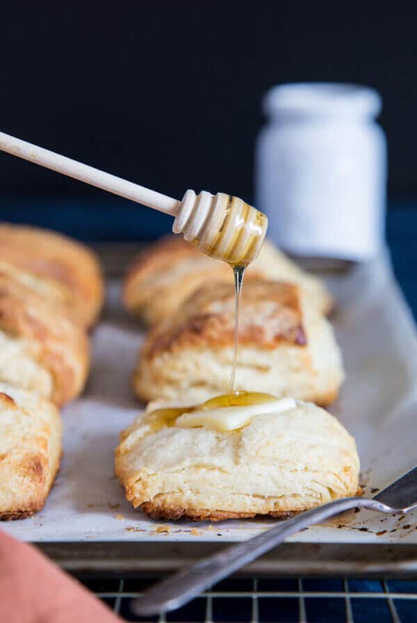 Honey buttermilk biscuits on a cooling rack being drizzled with honey