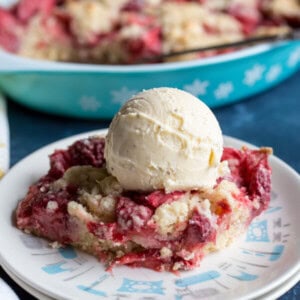 Strawberry dump cake on a plate with a scoop of vanilla ice cream on top