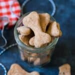 Bacon dog treats in a jar on a blue background.