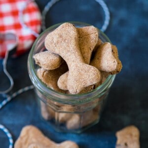 Bacon dog treats in a jar on a blue background.
