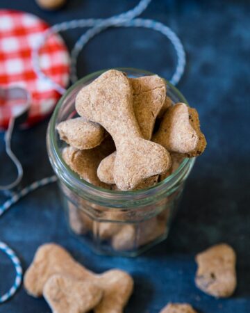 Bacon dog treats in a jar on a blue background.