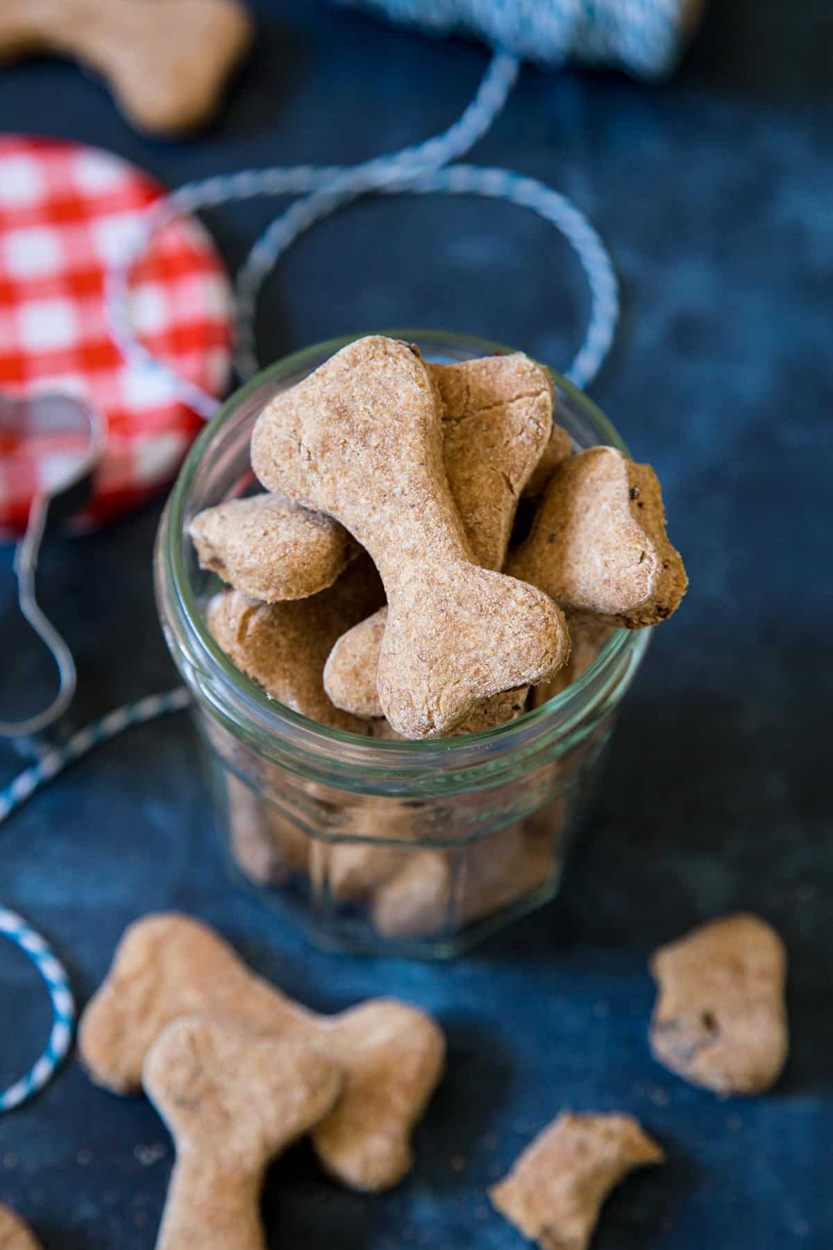 Bacon dog treats in a jar on a blue background.