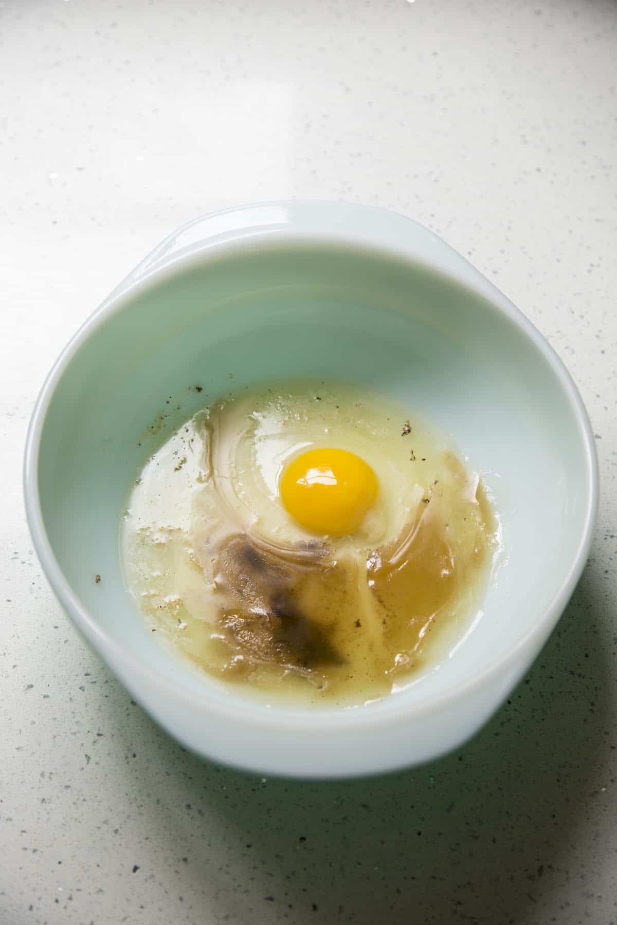 Bacon fat, egg and stock in a mixing bowl.