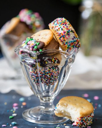 Ritz crackers ice cream sandwiches in a sundae glass next to a half eaten ice cream sandwich