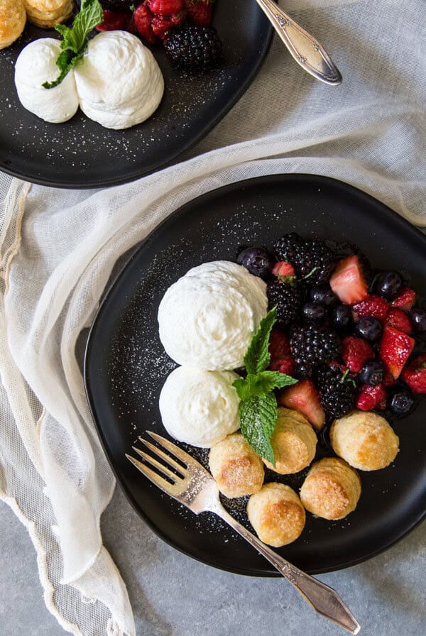Berries and cream with whipped cream and biscuits on a plate, garnished with mint leaves
