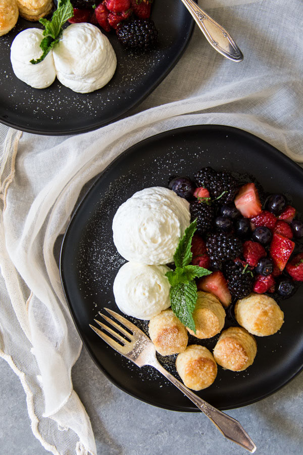 Berries and cream with whipped cream and biscuits on a plate, garnished with mint leaves