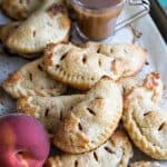 A pile of peach hand pies on a baking sheet