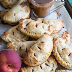 A pile of peach hand pies on a baking sheet