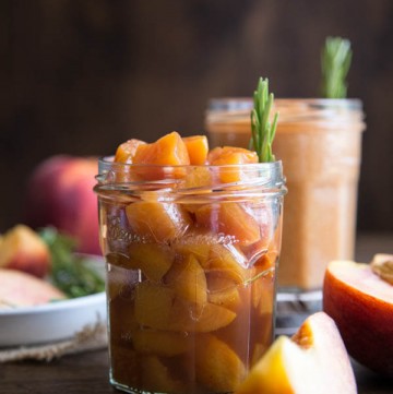 Peach compote in a glass jar with a rosemary sprig
