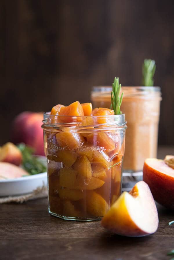 Peach compote in a glass jar with a rosemary sprig