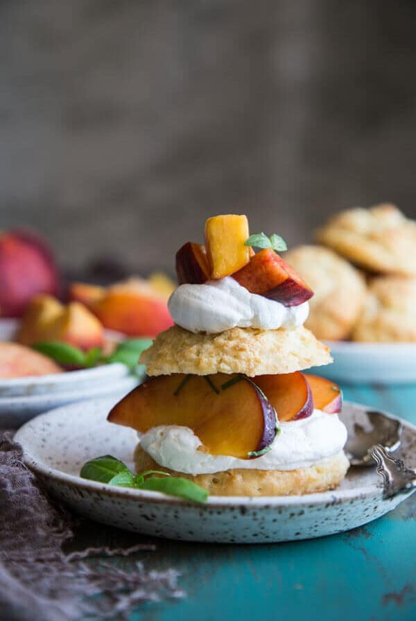 Fresh peach shortcake on a plate with basil leaves
