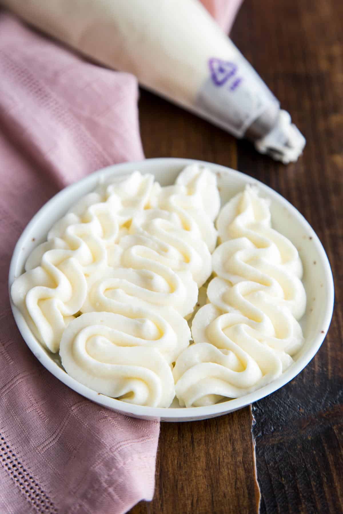 Cream cheese frosting piped on a plate.