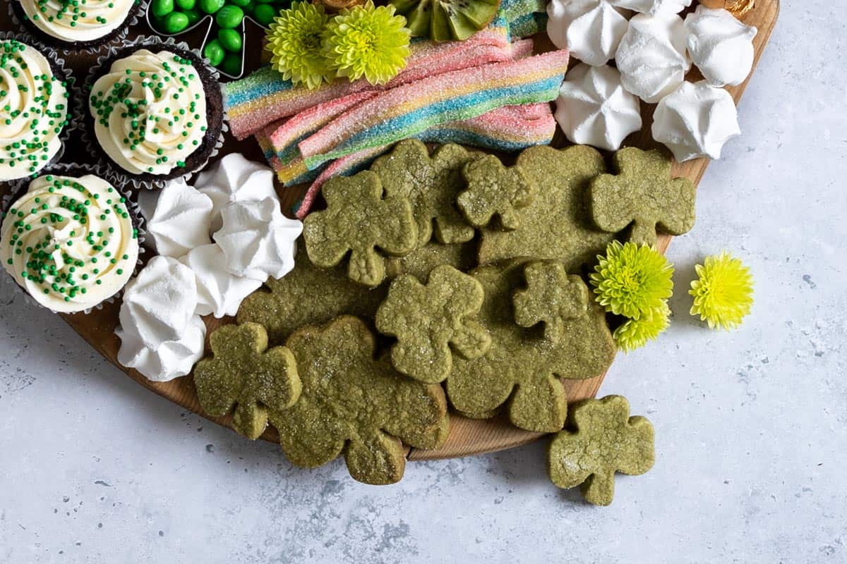 Matcha shortbread in clover leaf shapes on a dessert board.