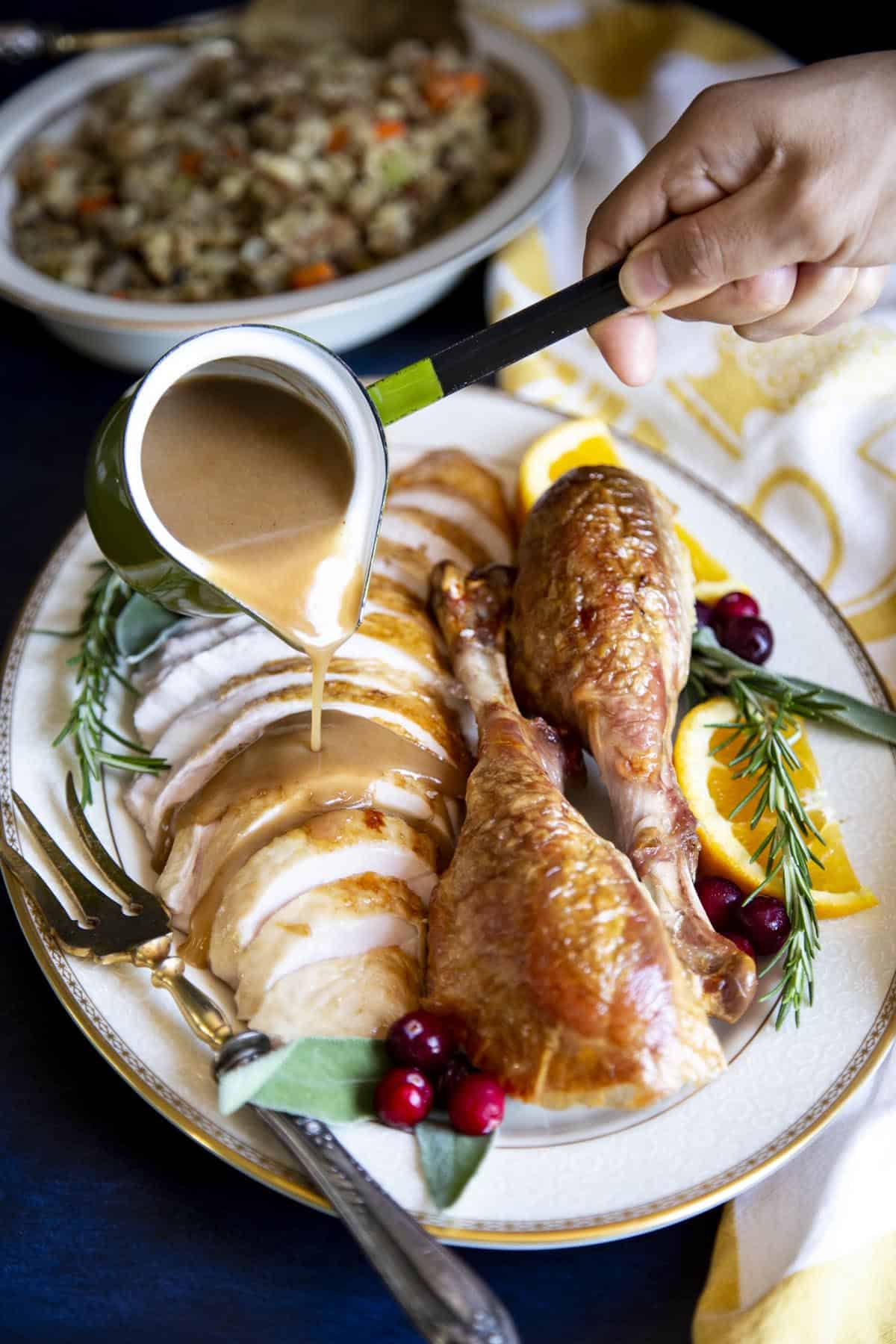 Ryan’s Thanksgiving Roast Turkey has been keeping our family full and happy for almost 10 years! This year we decided to share this recipe with you because it really is a tried and true recipe to keep for generations. #wildwildwhisk #thanksgiving #thanksgivingturkey #roastturkey #roastturkeyrecipe Gravy being poured over the turkey on a platter