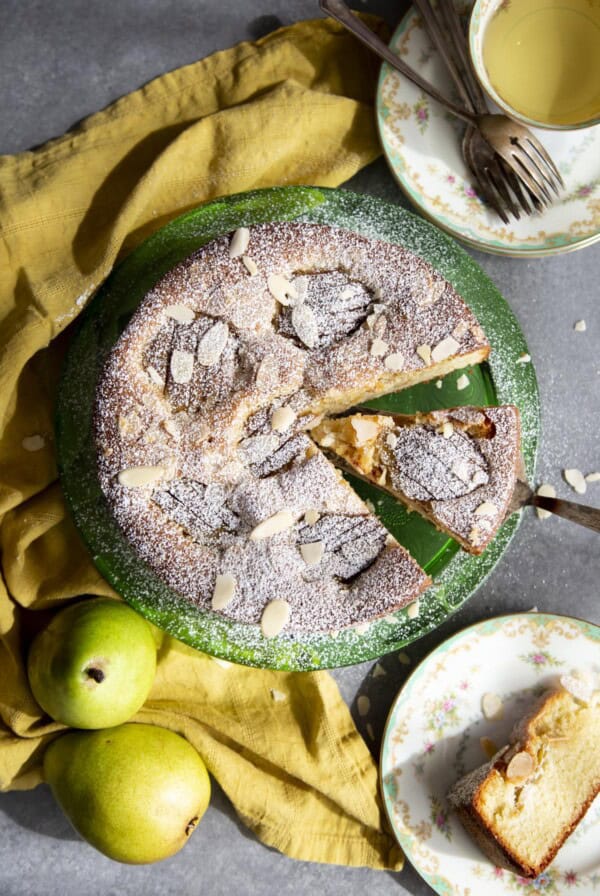Arial view of a pear cake on a green platter with a slice being served