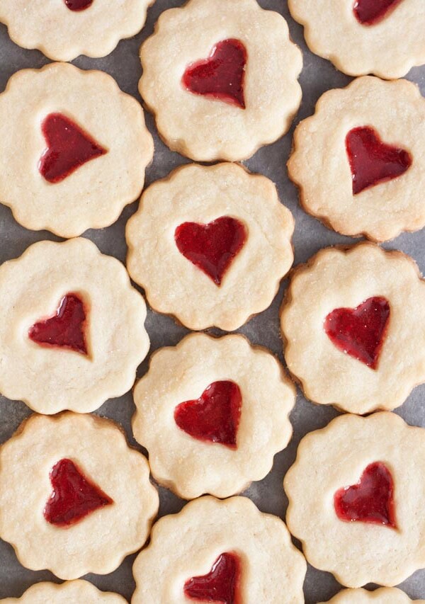 Stained glass cookies with heart shaped candy in the middles laying flat on a grey surface
