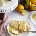 A slice of lemon cake on a plate, a bite is taken off and on a fork