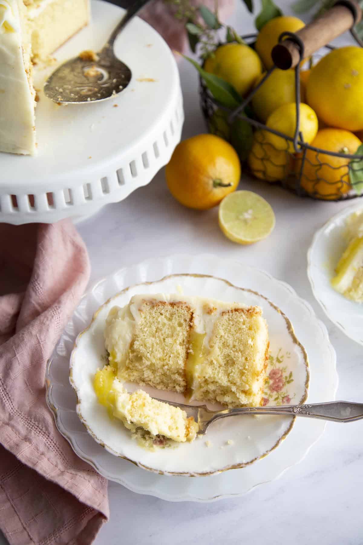 A slice of lemon cake on a plate, a bite is taken off and on a fork