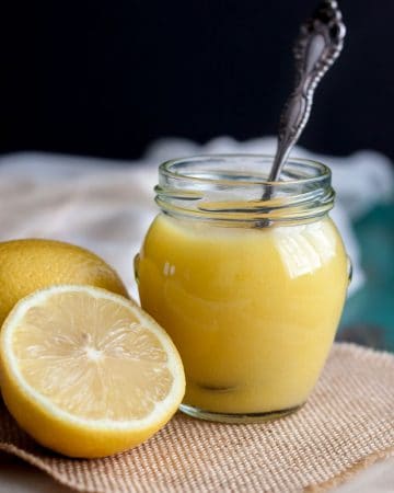 Lemon curd in a jar next to some lemons