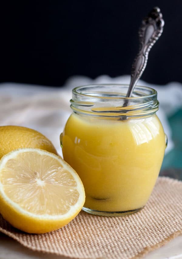 Lemon curd in a jar next to some lemons