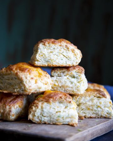 A stack of cheese biscuits on a wooden board.