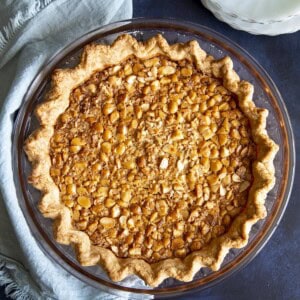 A macadamia pie next to a light blue towel on a dark blue surface.
