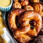 A pretzel in a tray with pretzel bites at the bottom.