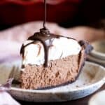 A slice of french silk pie with ganache drizzled on top.