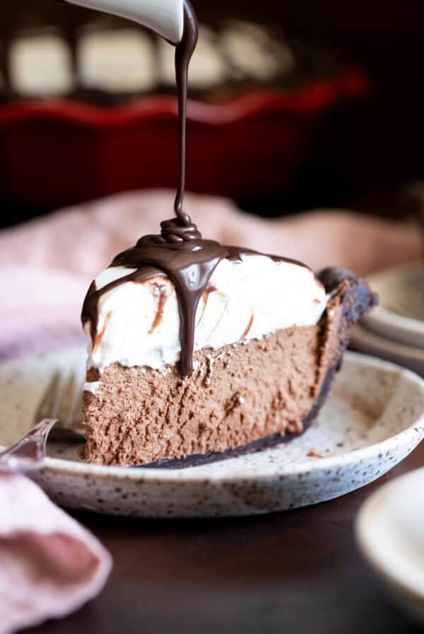 A slice of french silk pie with ganache drizzled on top.
