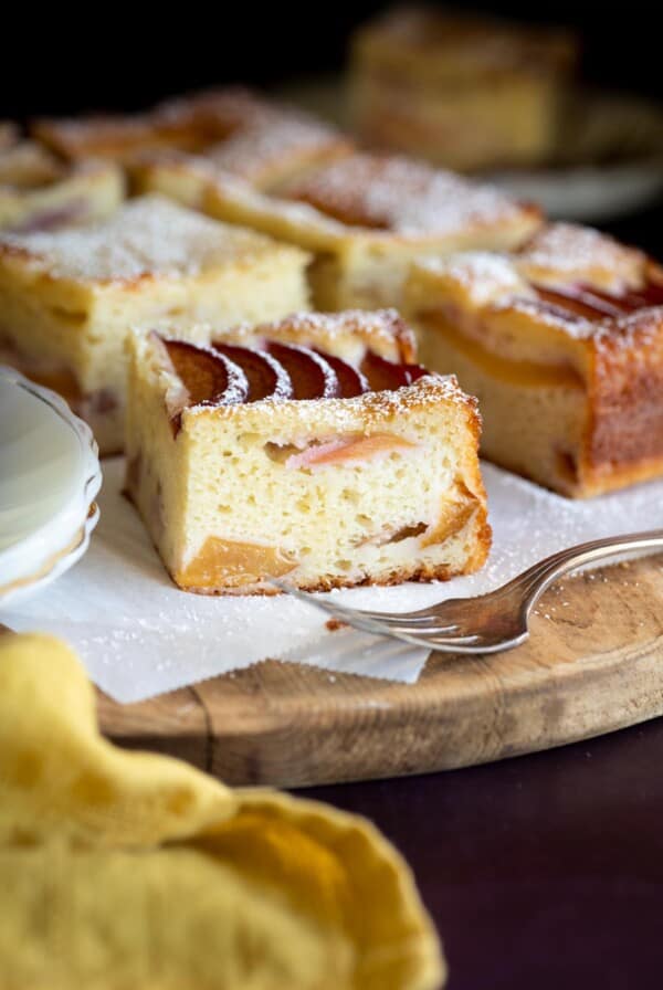 A slice of yogurt plum cake next to a fork.