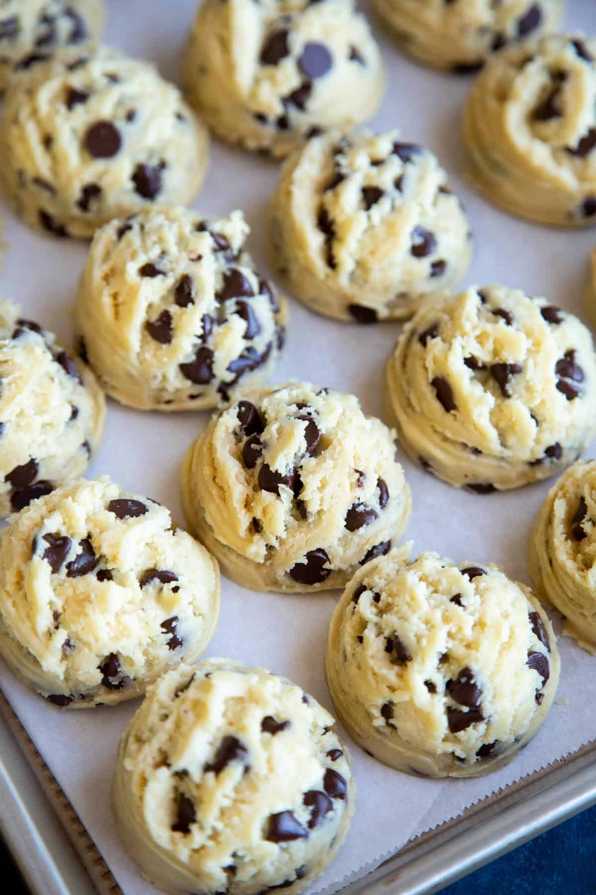 Chocolate chip cookie dough portioned into balls on a baking sheet.