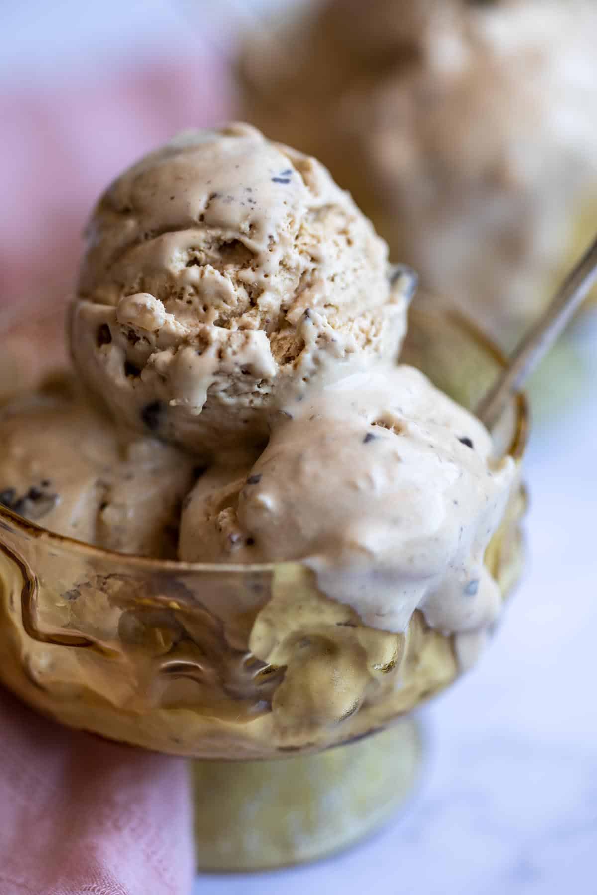 Close up of coffee macadamia ice cream in a yellow glass bowl.