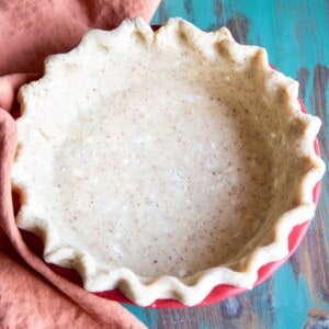 An unbaked pecan pie crust next to an orange towel.