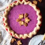 A purple sweet potato pie decorated with maple leaves cookies and pecans.