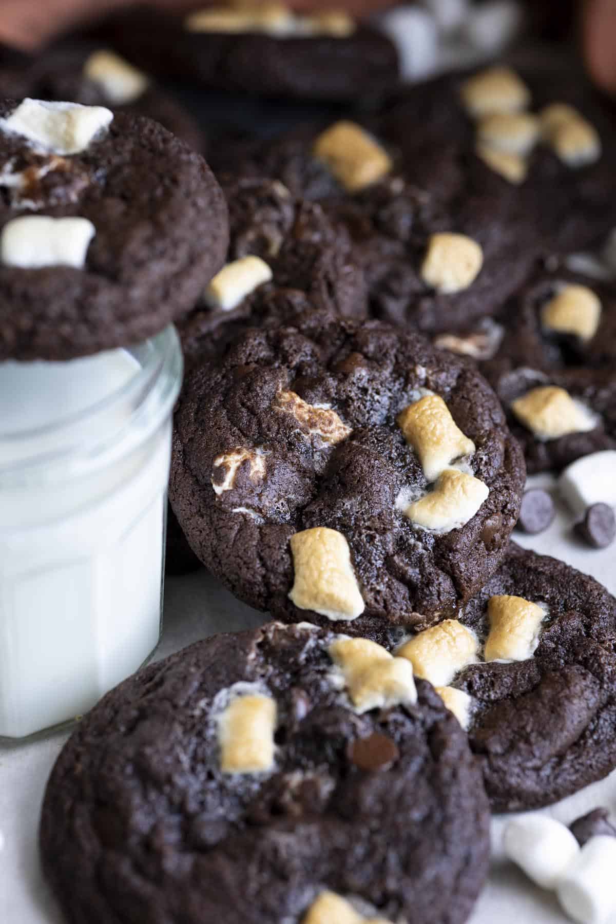Chocolate chip marshmallow cookies next to a glass of milk. 