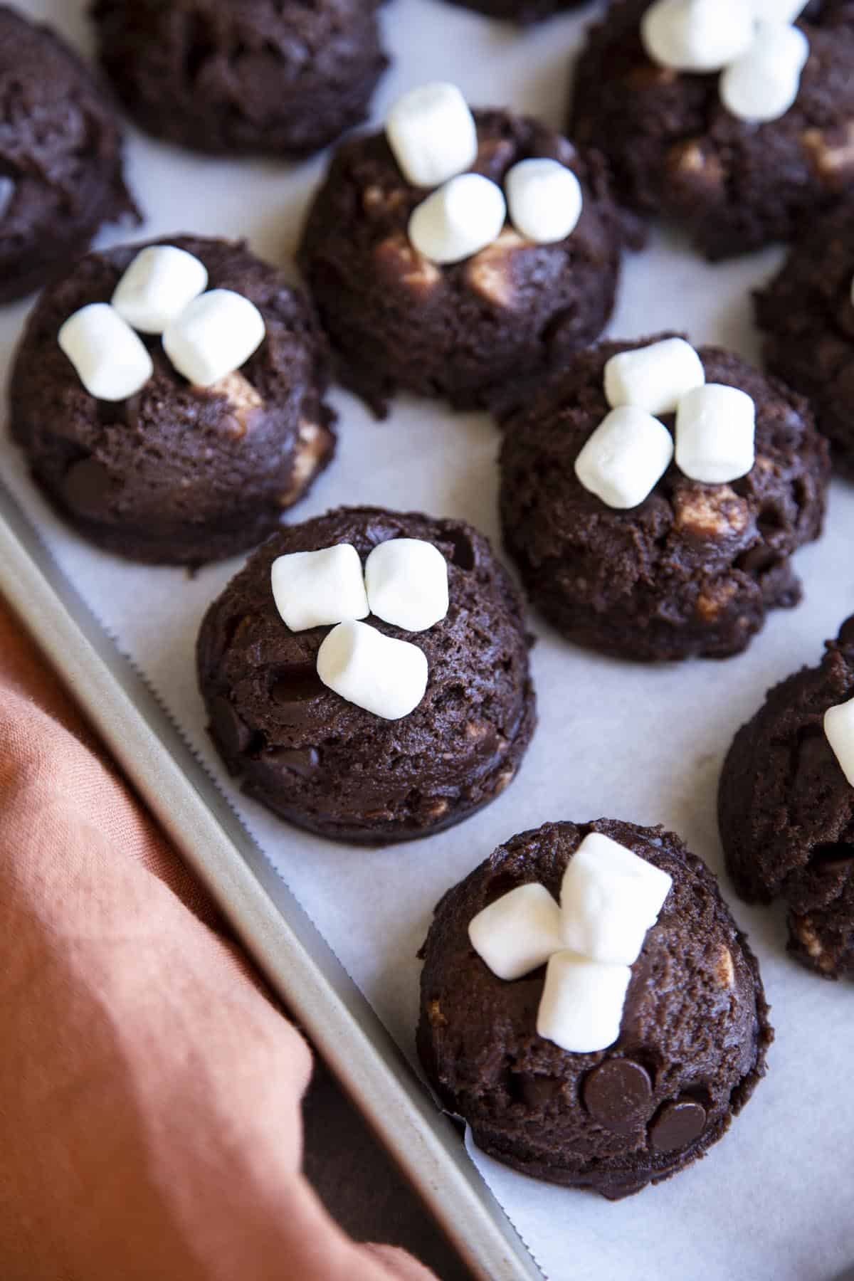 Chocolate marshmallow cookie dough balls with mini marshmallows on top.