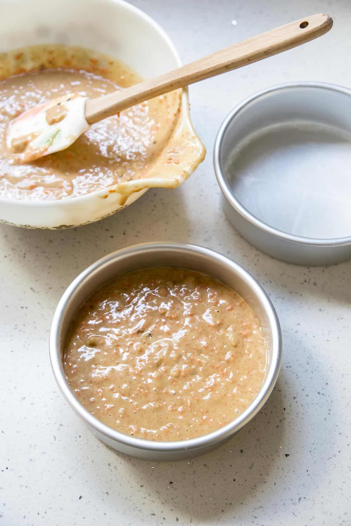 Dividing carrot cake batter into 6 inch cake pans.
