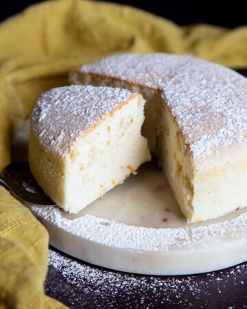 A fluffy Japanese cheesecake cut open on a marble plate.