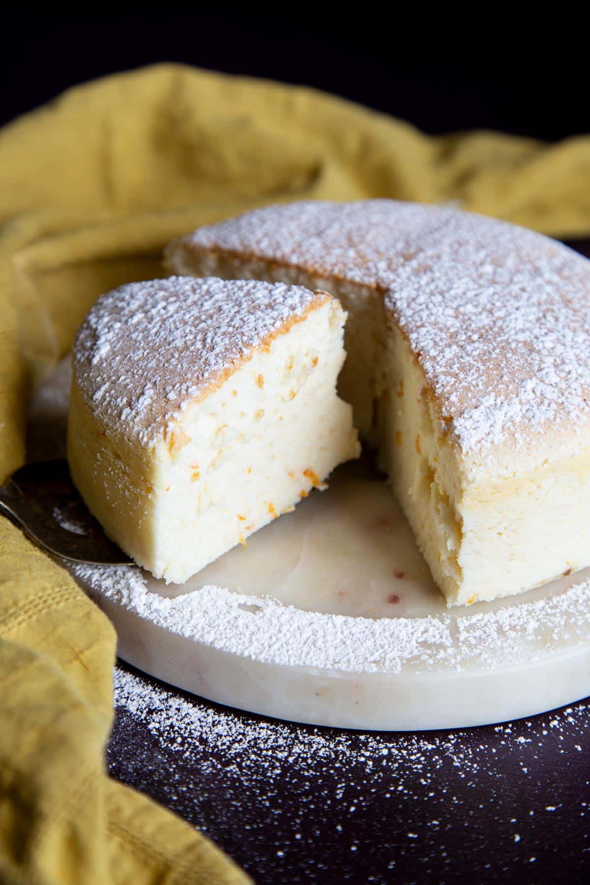 A fluffy Japanese cheesecake cut open on a marble plate.