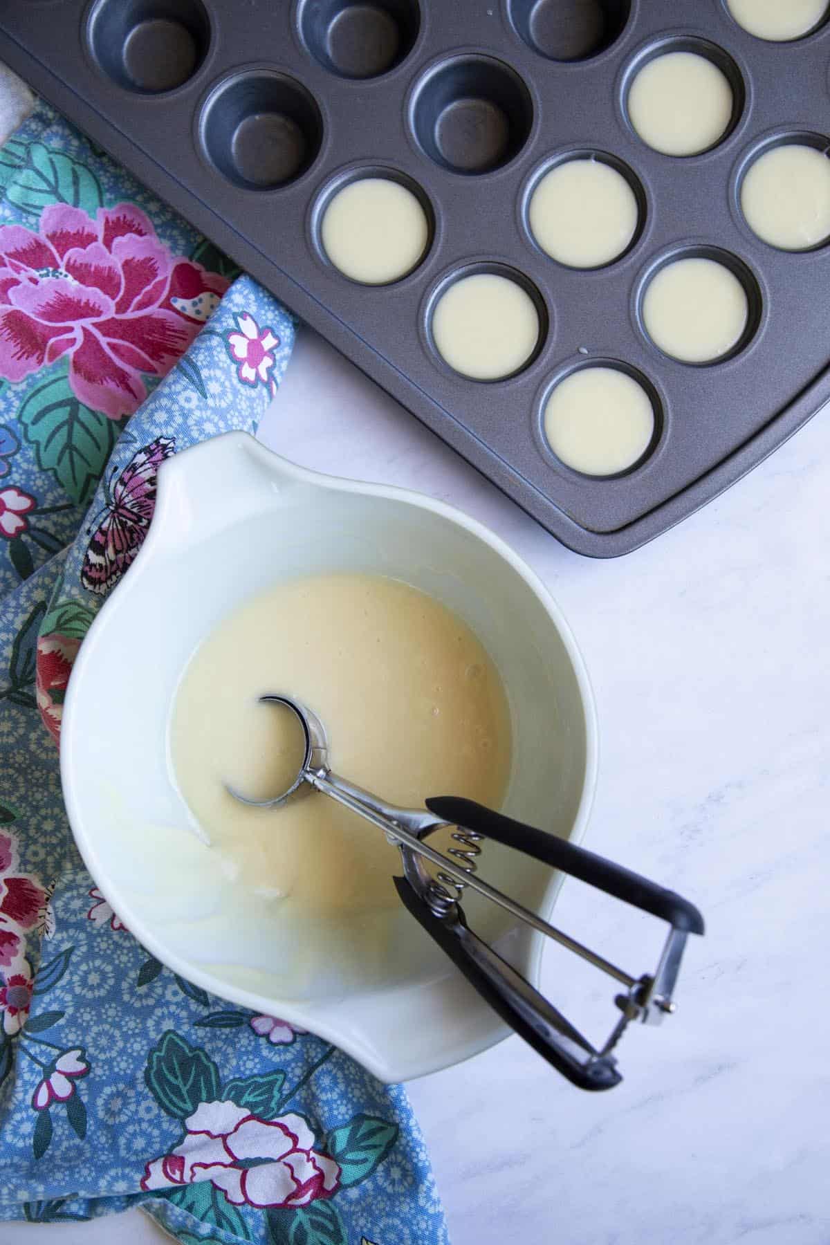Dividing mochi cake batter in mini muffin tins.