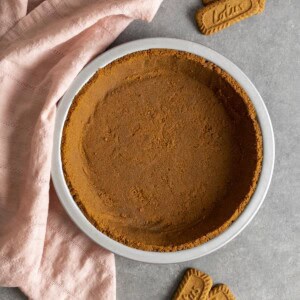 Biscoff pie crust on a gray table top with a pink tea towel.