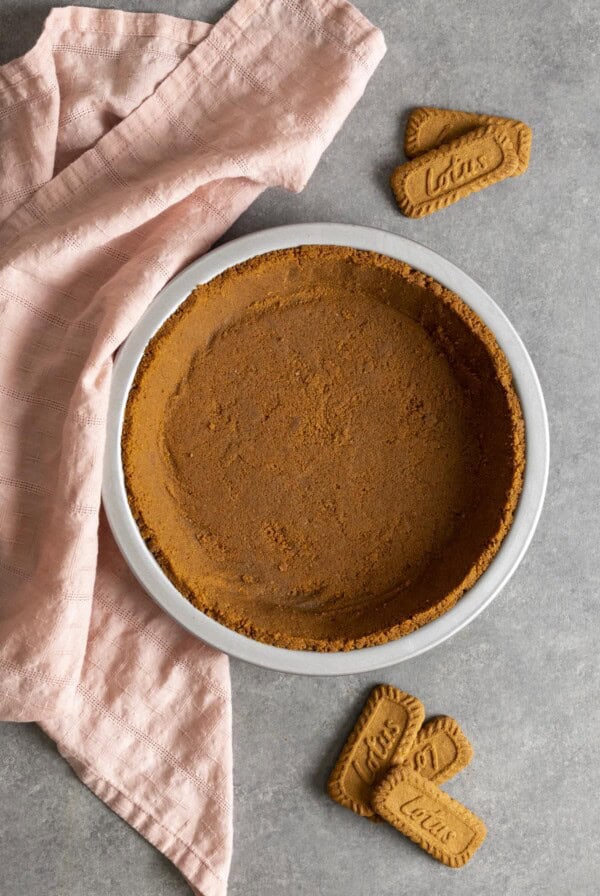 Biscoff pie crust on a gray table top with a pink tea towel.
